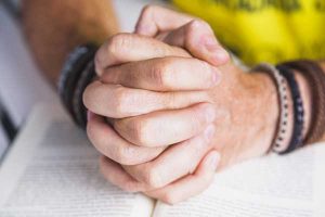 Praying hands on book