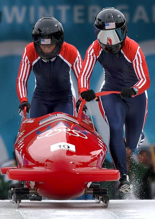 Two competitors power down the track at the start of an Olympic bobsled event for women